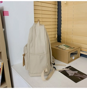 Detail of off-white nylon backpack side pocket with brown drawstring and stable structure