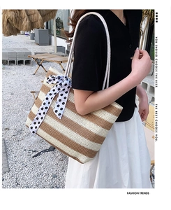 Detail of striped straw tote bag with polka dot ribbon and white rope handle design