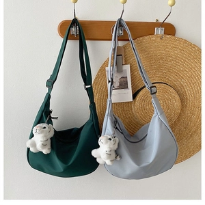 Detail of minimalist nylon crescent bags in green and blue with plush tiger charms