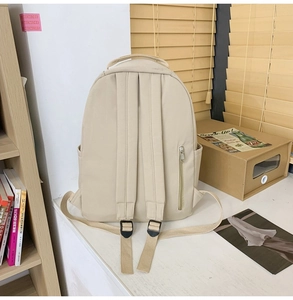 Detail view of beige nylon backpack back showing padded straps and hidden zipper pocket