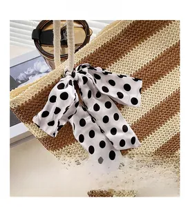 Detail of woven straw tote bag featuring striped texture and a polka dot silk scarf