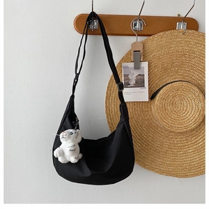 Detail of black nylon crescent bag with adjustable strap and cute plush charm detail