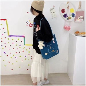 Détail du sac en velours bleu avec motif d'ours et pendentif en peluche au studio