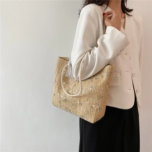 Sac fourre-tout en paille d'été avec dentelle et broderie florale porté par un mannequin