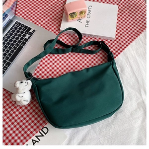 Detail of green nylon crescent bag with adjustable strap and cute white tiger plush charm
