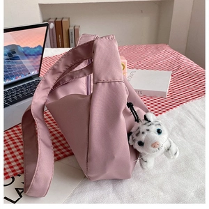 Detailed view of pink nylon crescent bag featuring a cute white tiger plush charm accessory