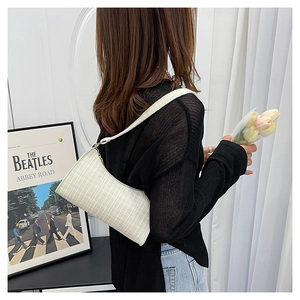 Detail showing white textured tweed baguette bag on shoulder with vintage casual aesthetic