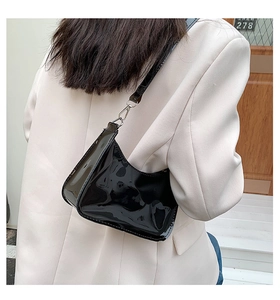 Detail of glossy black patent leather baguette bag with silver metallic hardware hooks