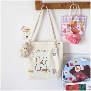 Détail du sac cabas en velours côtelé blanc cassé avec imprimé ours et breloque peluche