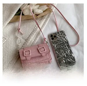 Détail du mini sac en tweed rose à côté d'un smartphone montrant sa taille compacte