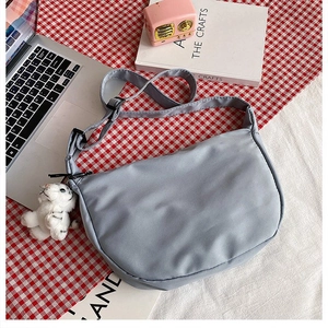 Detailed top view of grey-blue nylon crescent bag with adjustable strap and plush charm