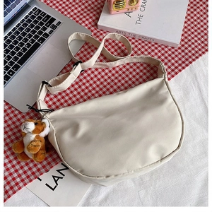Detail of off-white nylon crescent bag with cute plush tiger pendant on side