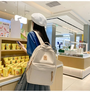 Detailed view of cream nylon backpack with wide straps and spacious side water bottle pocket