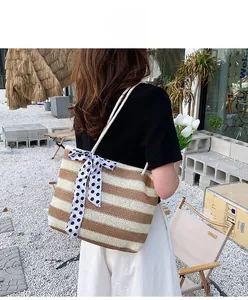 Detail of a woven straw tote bag with brown stripes and a polka dot silk bow decoration