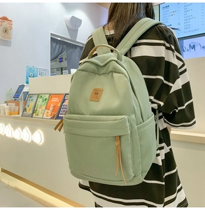 Detail of light green waterproof nylon backpack with leather logo patch and zipper pull