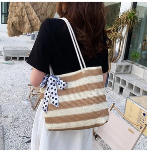 Detail of hand-woven straw tote bag with striped pattern and polka dot bow ribbon