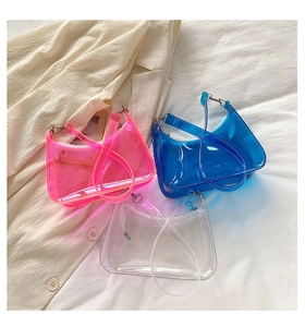 Three colors of transparent PVC jelly shoulder bags in pink, blue, and clear on fabric