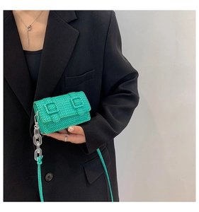 Détail du mini sac tressé vert émeraude avec boucles décoratives et bandoulière en résine