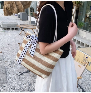 Detail of striped straw tote bag featuring a polka dot ribbon and soft rope handles