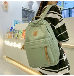 Detail of light green nylon backpack with front pocket and leather logo for girls