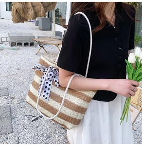 Close-up of woven straw tote bag with brown stripes and a polka dot silk scarf