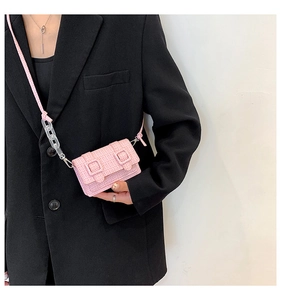 Détail du mini sac tressé rose avec chaîne acrylique et boucles décoratives
