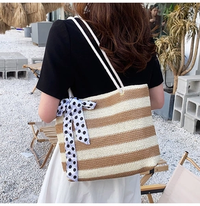 Detail of striped straw tote bag with cotton rope handles and blue polka dot ribbon scarf
