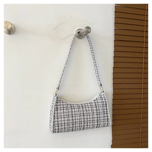 Detail of minimalist black and white tweed baguette bag showing texture and slim strap