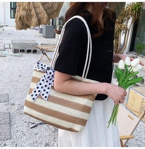 Detail of straw tote bag showing brown white stripes and polka dot ribbon bow