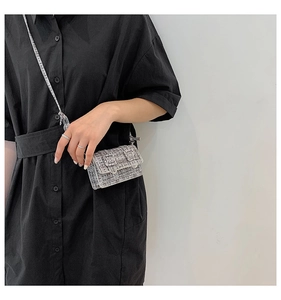 Détail du mini sac bandoulière en tweed gris avec boucles argentées sur fond blanc