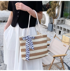 Detail of striped woven tote bag with blue polka dot bow and white rope handles