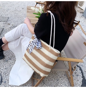 Outdoor shot of a woven striped tote bag with rope handles and decorative polka dot scarf