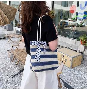 Detail of blue and beige striped straw tote bag featuring a dotted ribbon and cotton handles