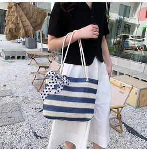 Close-up of blue and white woven straw tote bag with polka dot bow and cotton rope handles