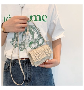 Gros plan d'un mini sac tissé crème avec doubles boucles et bandoulière en chaîne acrylique