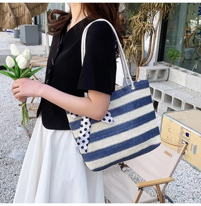 Detailed close-up of blue and white striped straw tote bag with polka dot bow and rope handles