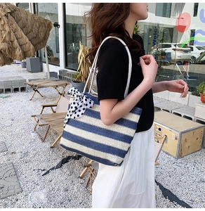 Detail of blue and white striped straw tote bag with polka dot scarf and rope handles
