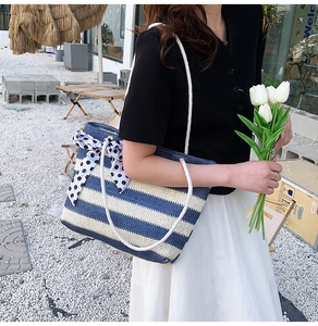 Detail of woven straw tote with blue and white stripes and a polka dot ribbon bow
