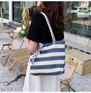 Blue and white striped straw tote bag featuring a polka dot bow and woven rope handles