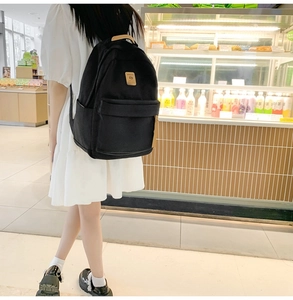 Side view of black nylon backpack with brown leather accents shown in casual setting