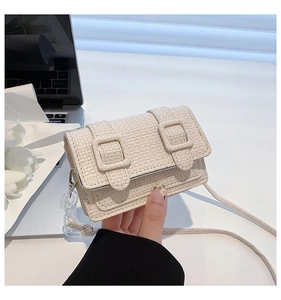 Détail du mini sac en tweed crème avec sangles et chaîne près d'un ordinateur et tulipes