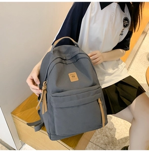Detail of grey fabric backpack with leather handle and branded MRMI BAG logo patch