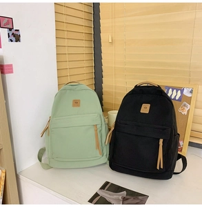 Close-up of green and black canvas backpacks with spacious main pockets and leather accents