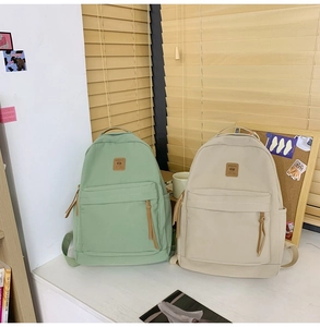Detail view of simple nylon backpacks in light green and cream white with logo patch