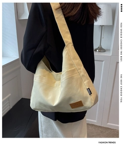 Detail view of large beige canvas tote bag with side pockets and sport logo labels