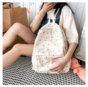 Detail view of cream canvas backpack with pink floral prints and braided zipper pulls