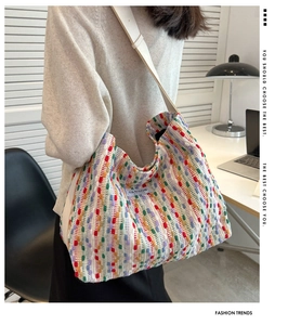 Detail of colorful tweed tote bag with woven stripes and white wide shoulder strap