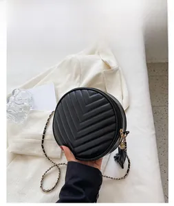 Detail of black round crossbody bag with V-shaped quilting and leather tassel pendant