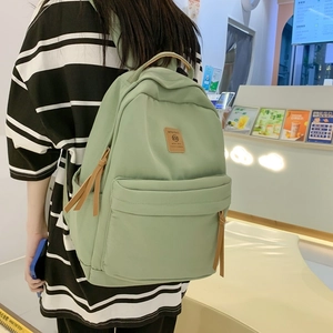 Minimalist mint green nylon backpack for girls with brown logo patch and zipper pulls