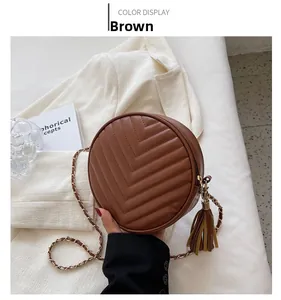 Macro shot of dark brown quilted round bag with chain strap and leather tassel detail